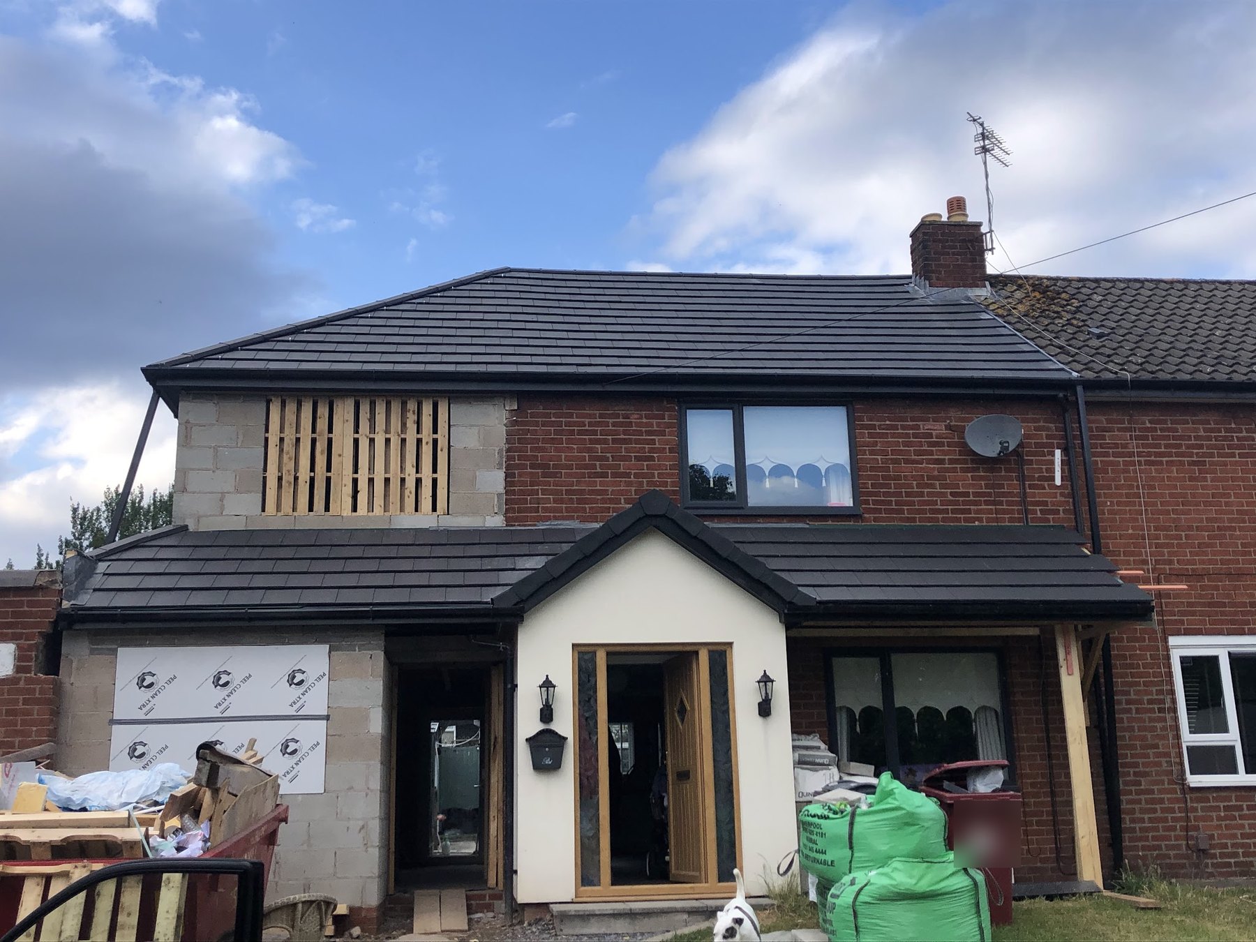 A semi-detached house with a new dark tiled roof and a matching porch roof