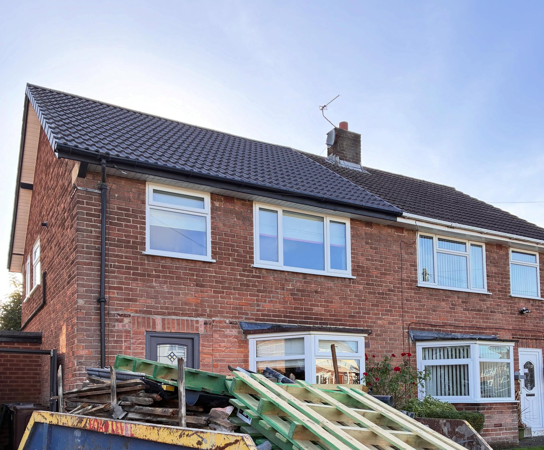 A brick semi-detached house with its new dark tiled roof on