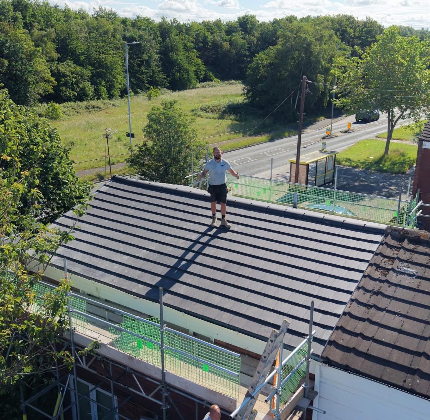 A finished tiled roof seen from the scaffold, with one of the roofers standing on it