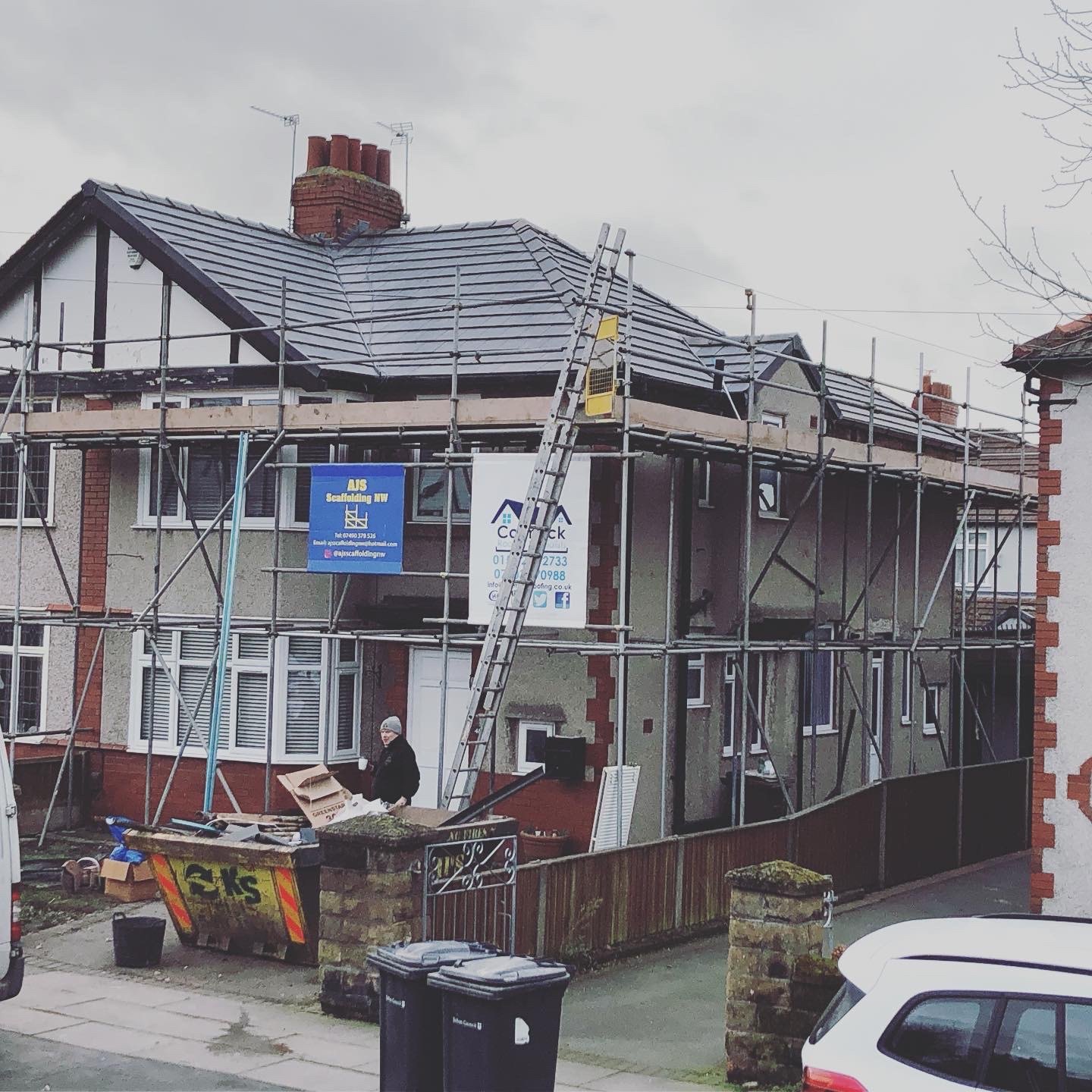 A hipped-roof semi scaffolded all round, new tiles on and the Cormack Roofing board on the front